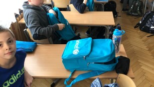 uśmiechnięte dzieci z niebieskimi plecakami z logo UNICEF