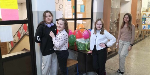 cztery uśmiechnięte uczennice stoją na korytarzy szkolnym